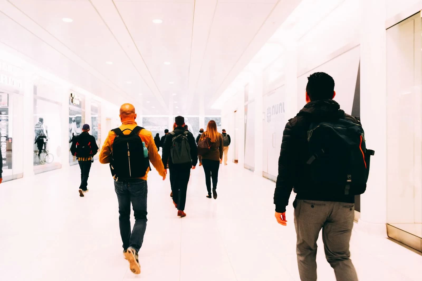 Passengers walking with luggage through a bright airport terminal